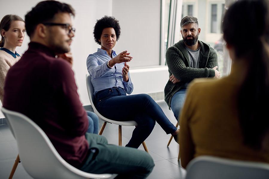 A diverse group of people sitting in chairs in a circle having a discussion